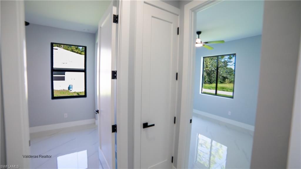 Hallway featuring healthy amount of natural light and marble finish flooring