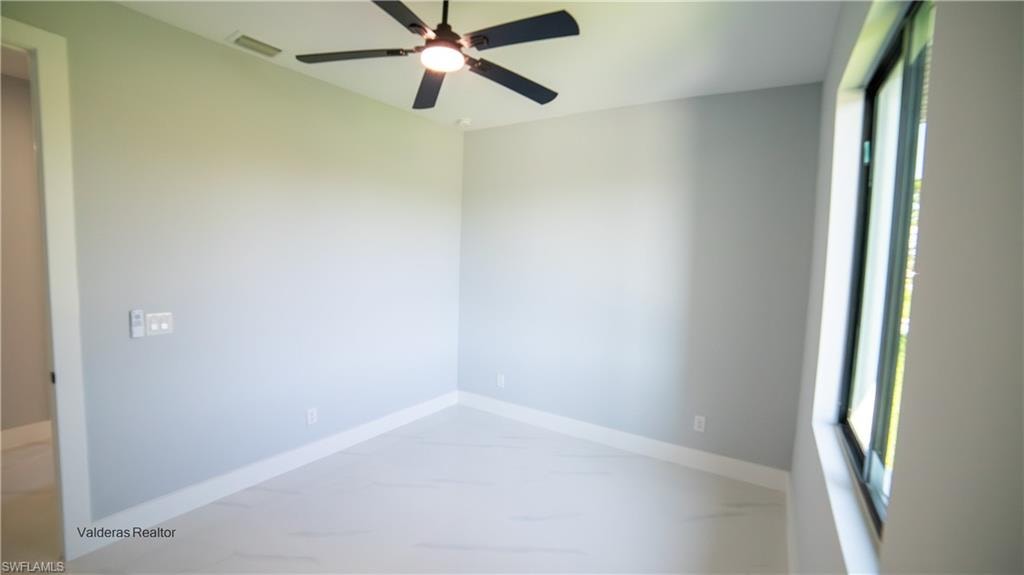 Unfurnished room with ceiling fan and plenty of natural light