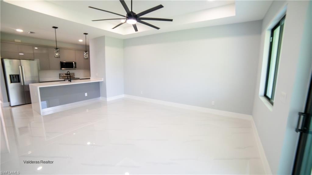 Unfurnished living room with recessed lighting, a raised ceiling, and a ceiling fan