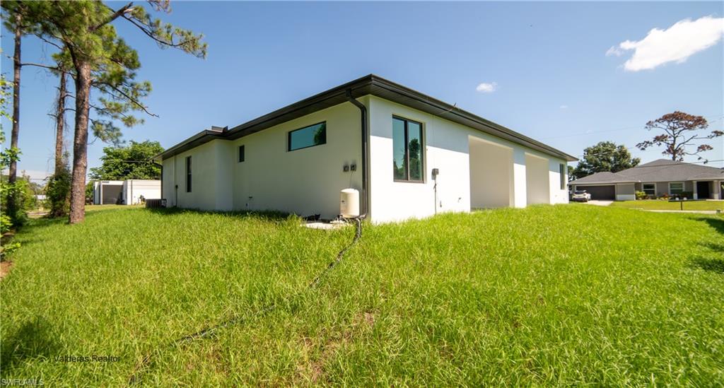 Back of property featuring a lawn and stucco siding