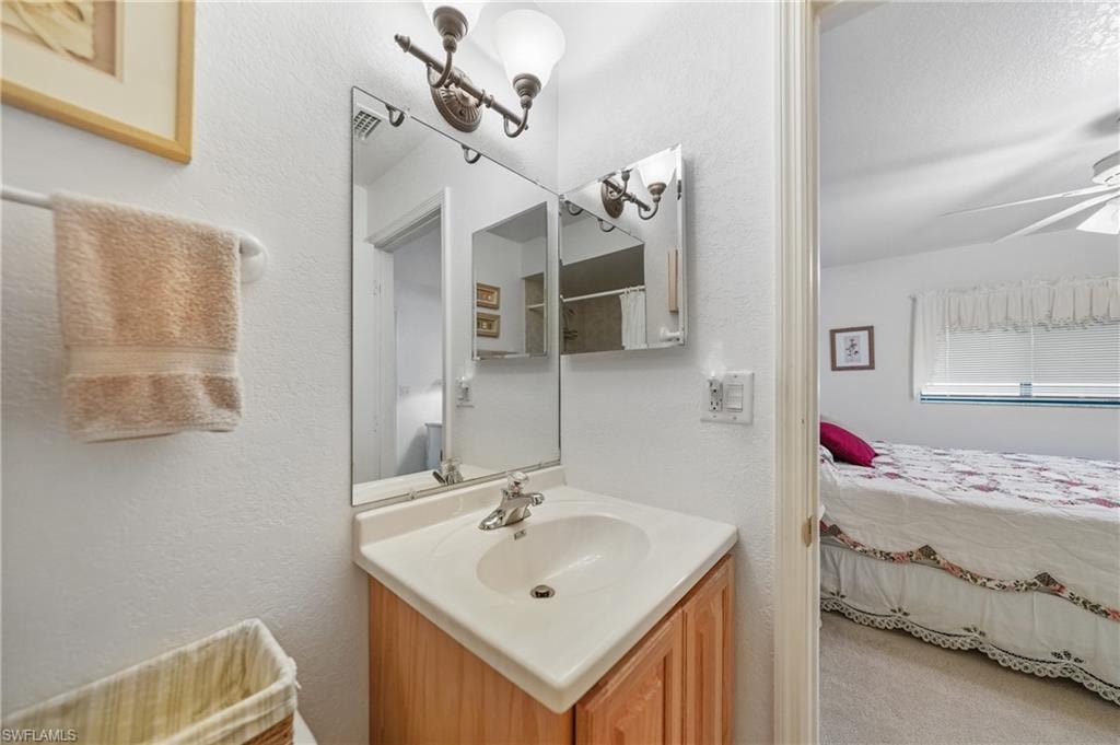 Ensuite bathroom with a textured wall, vanity, and a ceiling fan