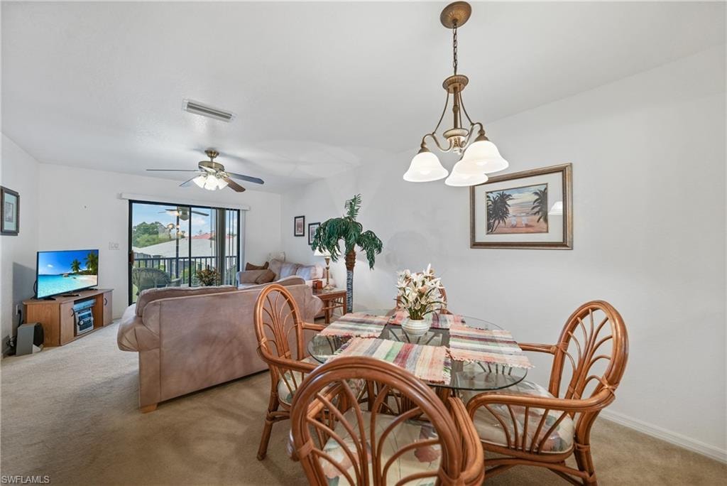 Dining area featuring light colored carpet, a chandelier, and a ceiling fan