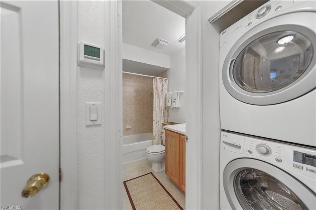 Washroom with estacked washer and dryer and light tile patterned flooring