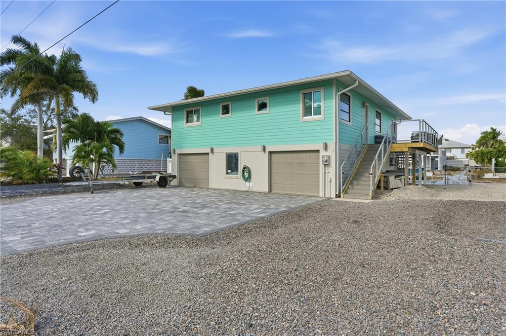Coastal inspired home with decorative driveway, stairway, and an attached garage - Virtually Edited Image