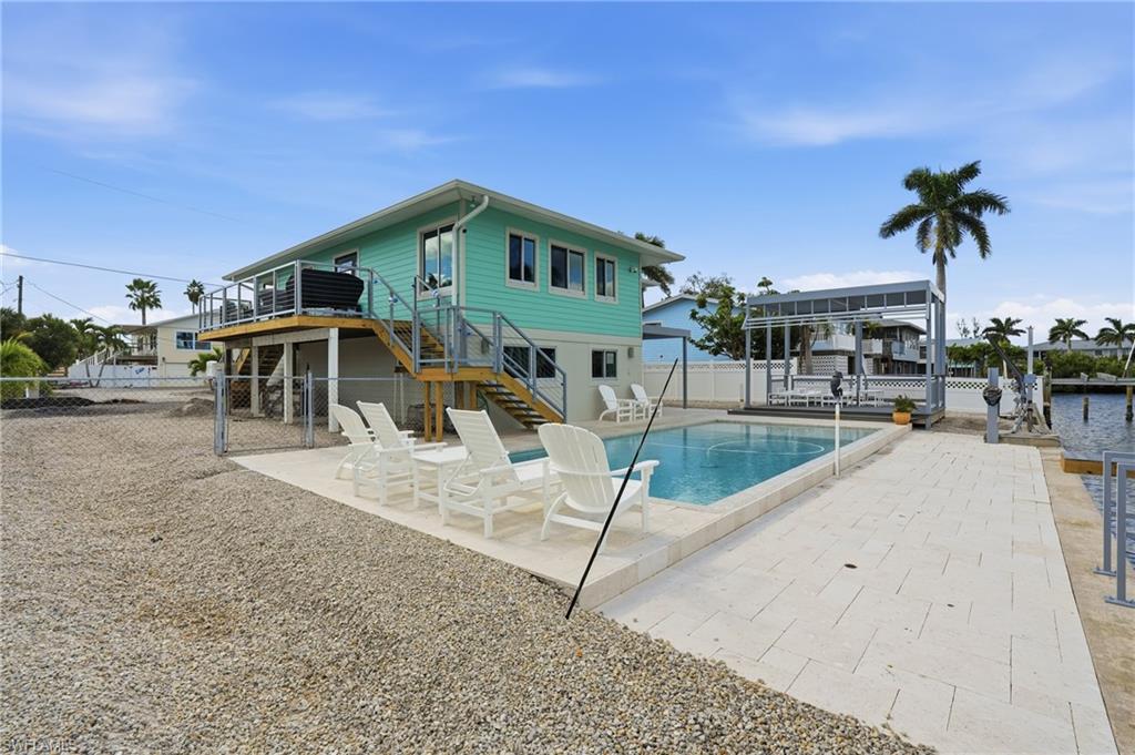 Pool featuring a patio area, a fenced backyard, stairs, and a gate - Virtually Edited Image