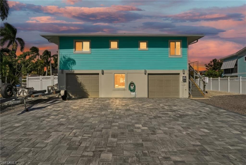 Coastal home featuring decorative driveway, stairway, and an attached garage - Virtually Edited Image