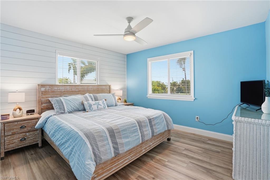 Bedroom with wood finished floors, a ceiling fan, and wood walls - Virtually Edited Image