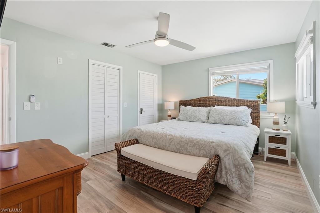 Bedroom featuring multiple closets, light wood-type flooring, and ceiling fan - Virtually Edited Image