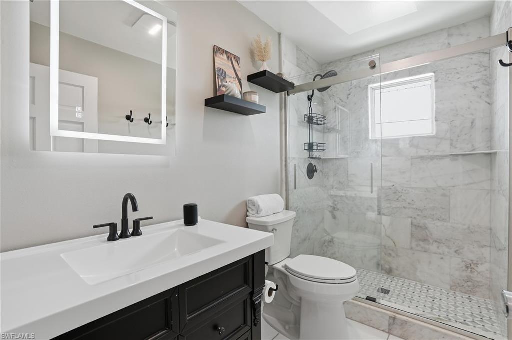 Bathroom with vanity and a marble finish shower - Virtually Edited Image