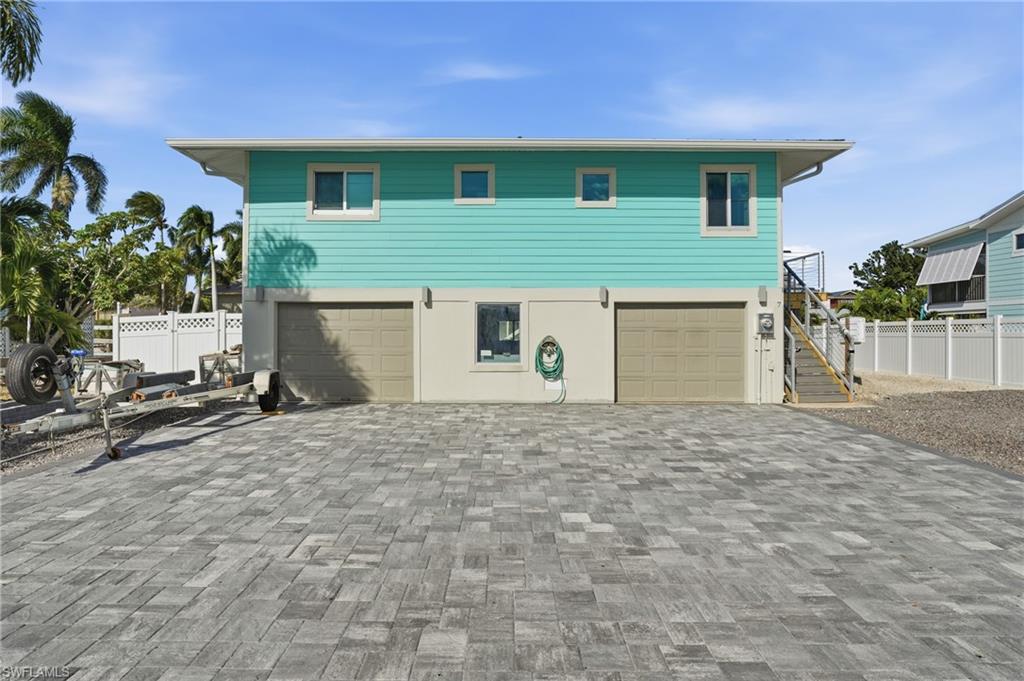 Coastal inspired home with decorative driveway, stairway, and an attached garage - Virtually Edited Image