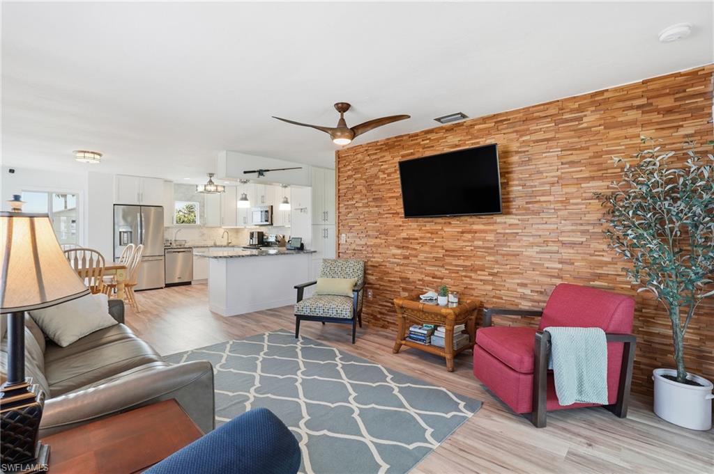 Living room featuring light wood-style flooring and ceiling fan - Virtually Edited Image