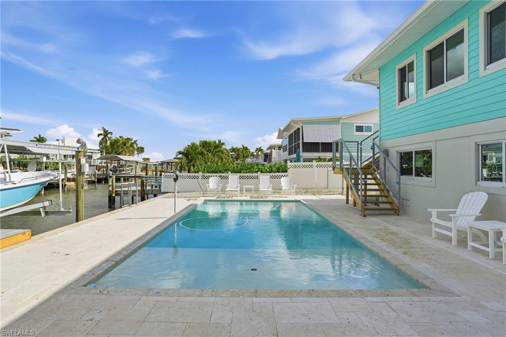 View of pool with boat lift, a patio, stairway, a dock, and a water view - Virtually Edited Image