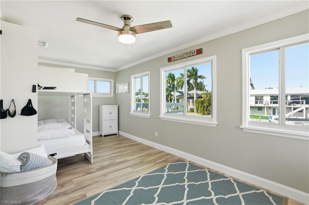 Den with crown molding, light wood-style flooring, and a ceiling fan - Virtually Edited Image