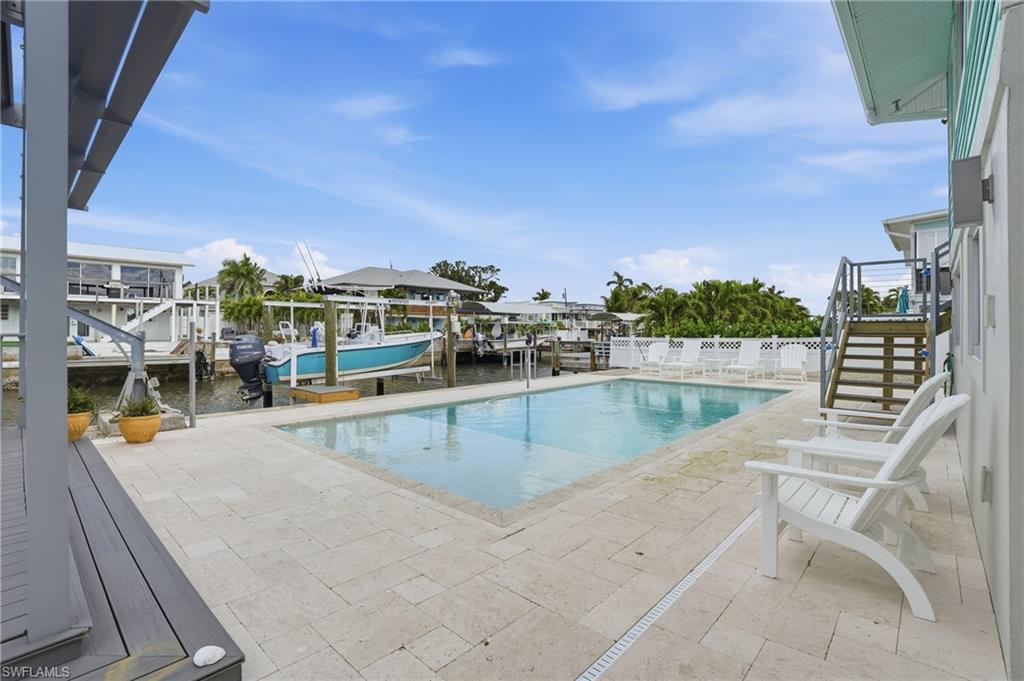 View of pool featuring boat lift, stairs, a water view, a dock, and a patio - Virtually Edited Image