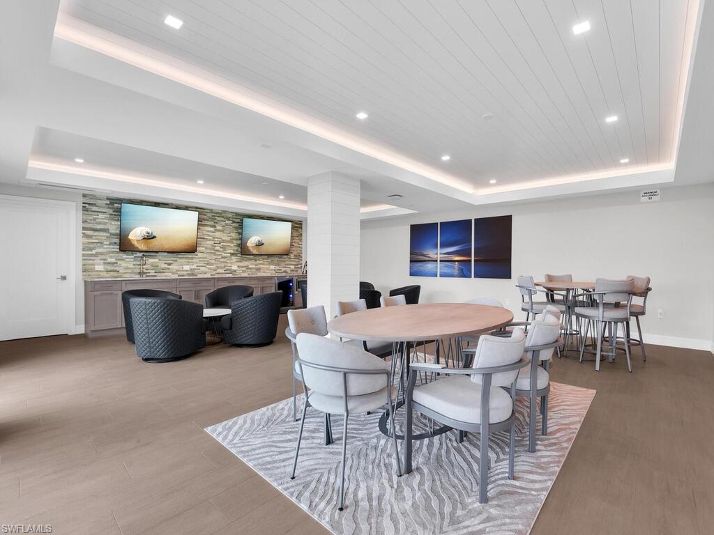 Dining area with a raised ceiling, light wood-style floors, and recessed lighting