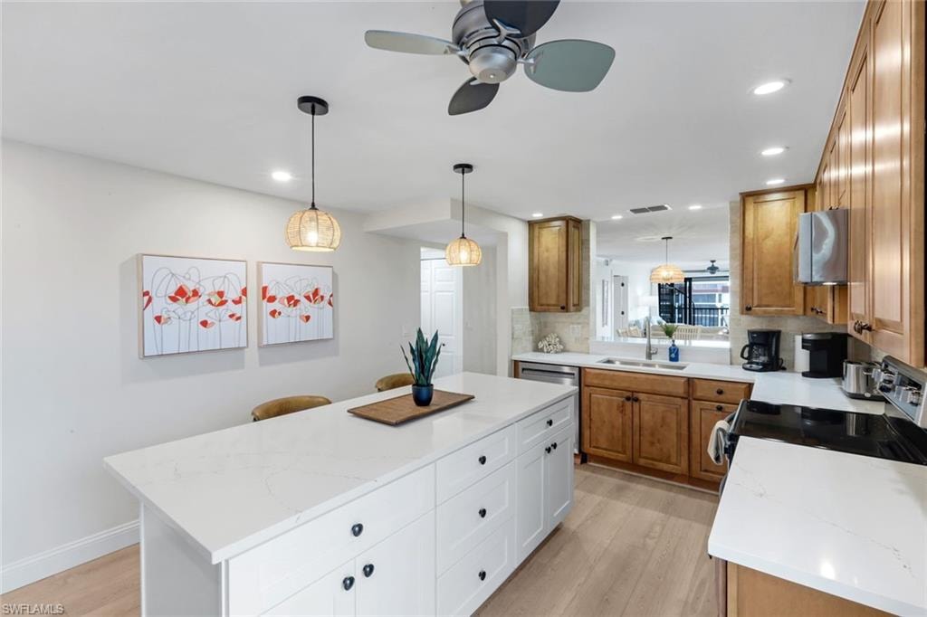 Kitchen with a ceiling fan, brown cabinets, white cabinets, hanging light fixtures, and recessed lighting