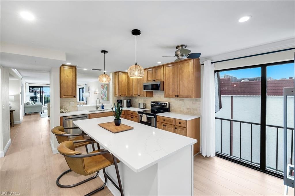 Kitchen featuring brown cabinets, hanging light fixtures, appliances with stainless steel finishes, backsplash, and recessed lighting