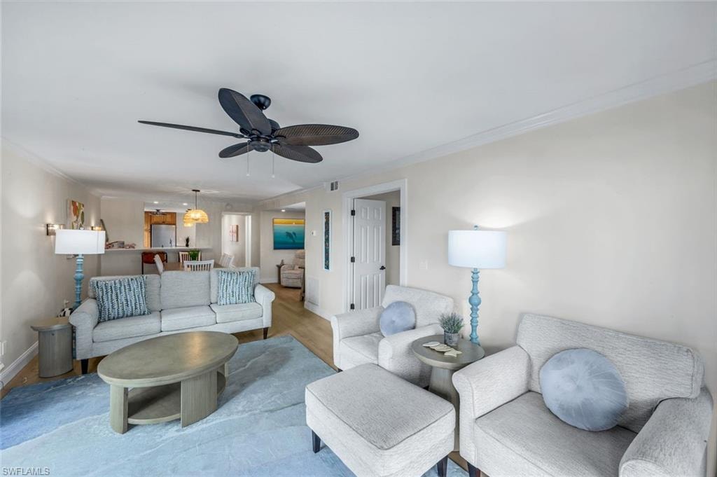 Living area with crown molding, wood finished floors, and a ceiling fan