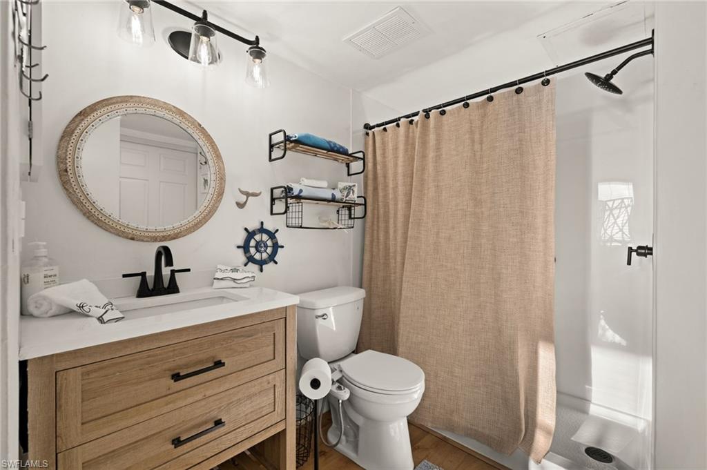 Full bathroom with a shower stall, vanity, and wood finished floors