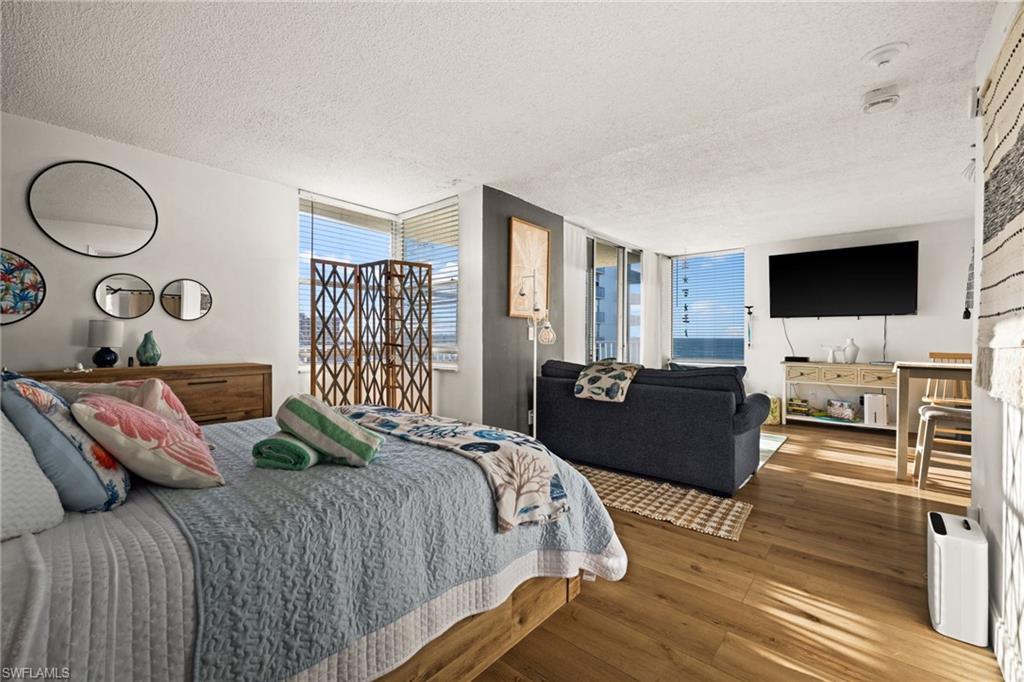 Bedroom with a textured ceiling, hardwood / wood-style floors, and a large fireplace