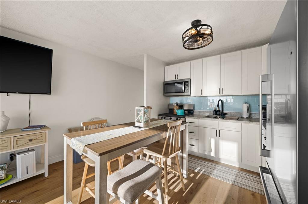 Kitchen featuring stainless steel appliances, white cabinetry, backsplash, light wood finished floors, and a textured ceiling