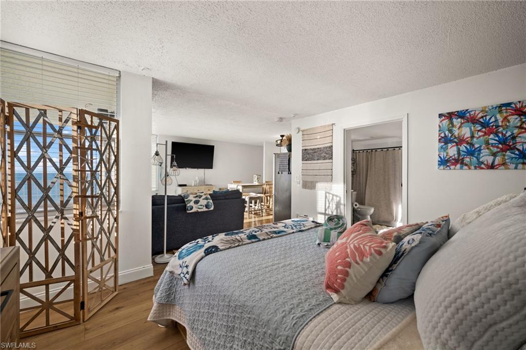 Bedroom with a textured ceiling, wood finished floors, and ensuite bath