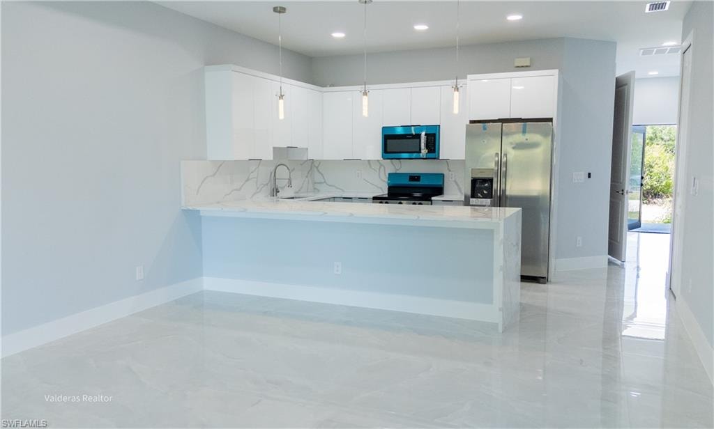 Kitchen with light stone countertops, stainless steel appliances, a peninsula, modern cabinets, and decorative backsplash