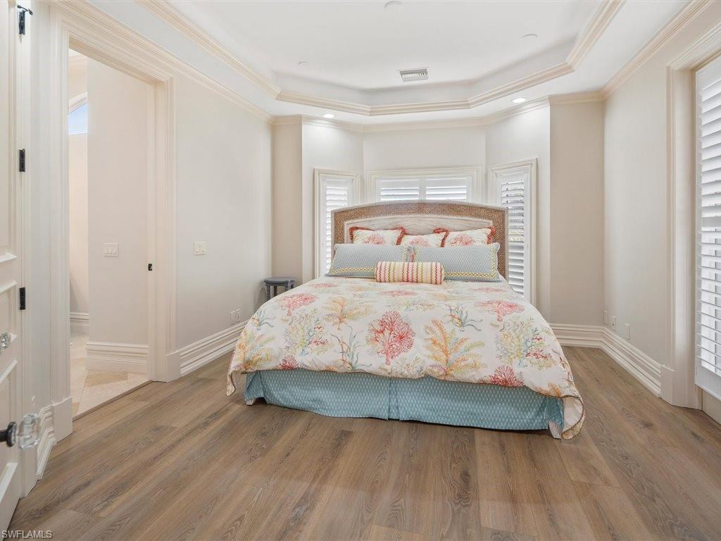 Bedroom featuring a raised ceiling, light wood finished floors, crown molding, and recessed lighting