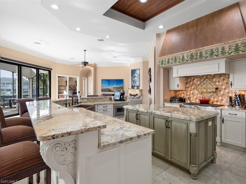 Kitchen with light stone countertops, white cabinetry, recessed lighting, a breakfast bar area, and decorative backsplash