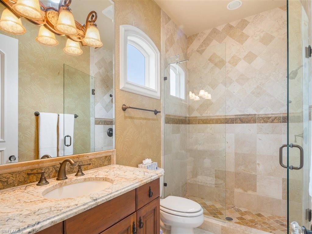 Full bathroom with vanity, a stall shower, and wallpapered walls