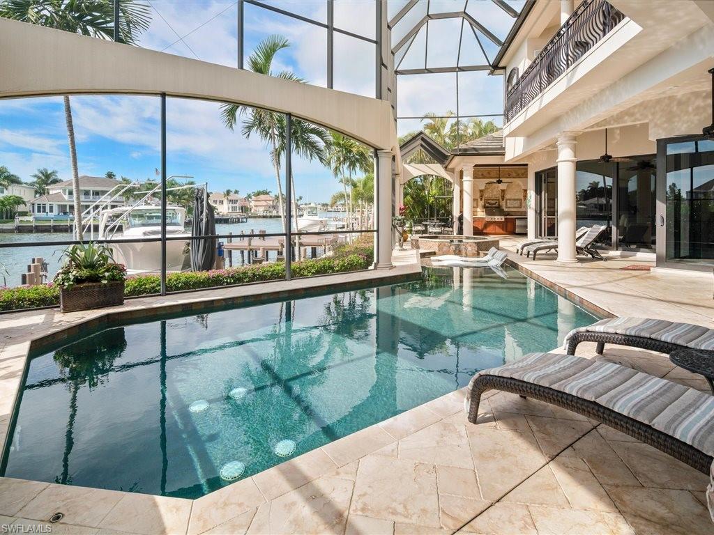 View of pool featuring glass enclosure, a sunroom, a patio area, a pool with connected hot tub, and a water view