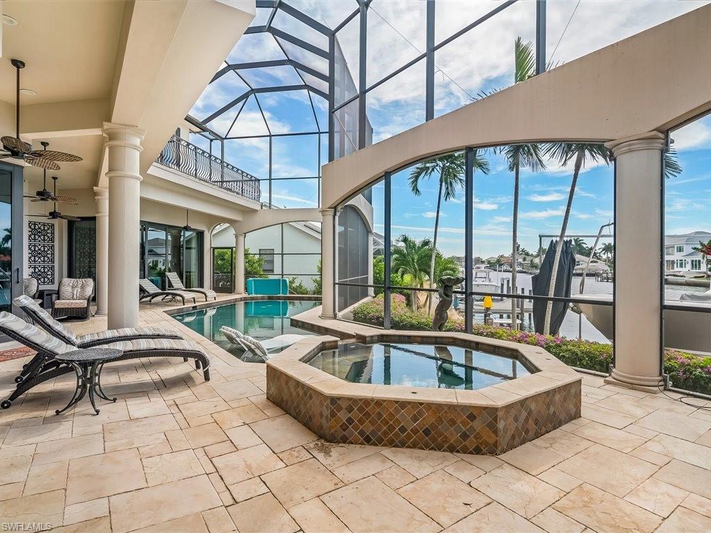 Swimming pool with a sunroom, a patio area, an in-ground hot tub, and glass enclosure