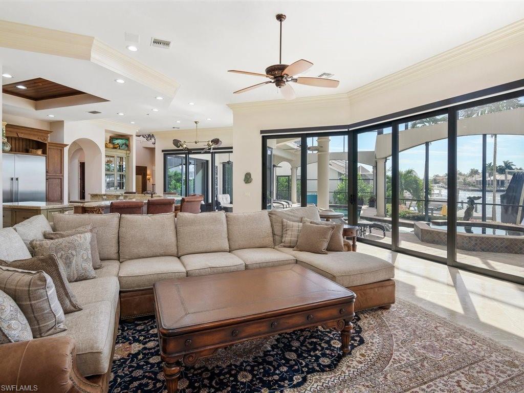 Living room with healthy amount of natural light, ornamental molding, arched walkways, ceiling fan, and recessed lighting