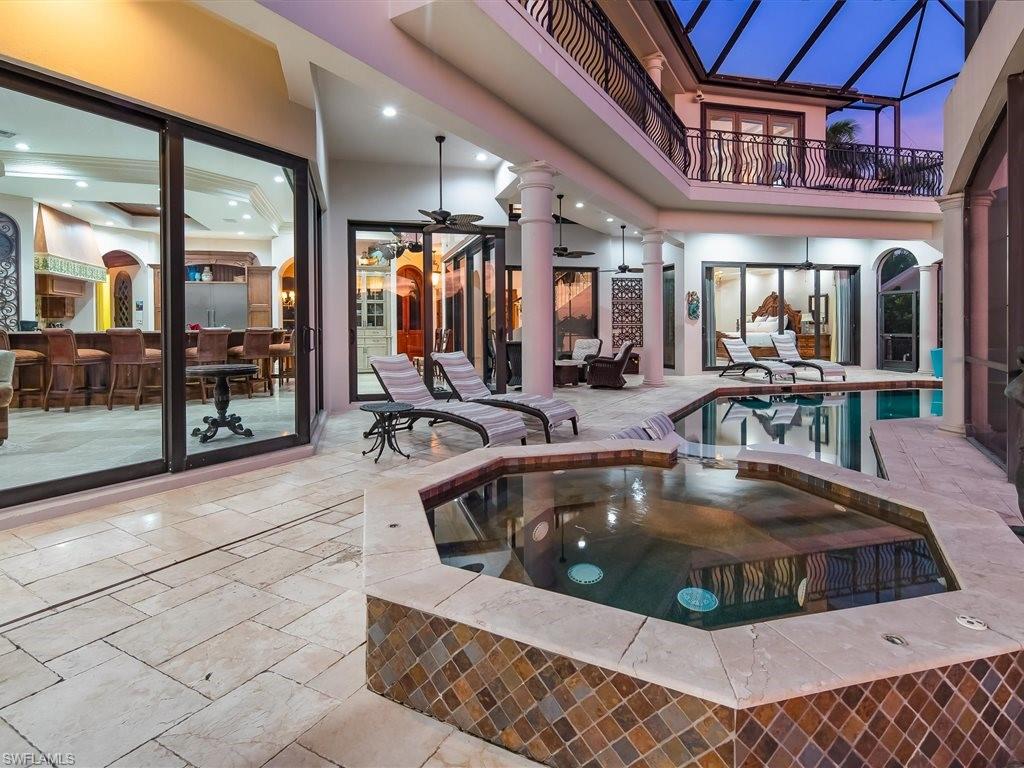 View of pool featuring a balcony, a patio area, a pool with connected hot tub, and glass enclosure