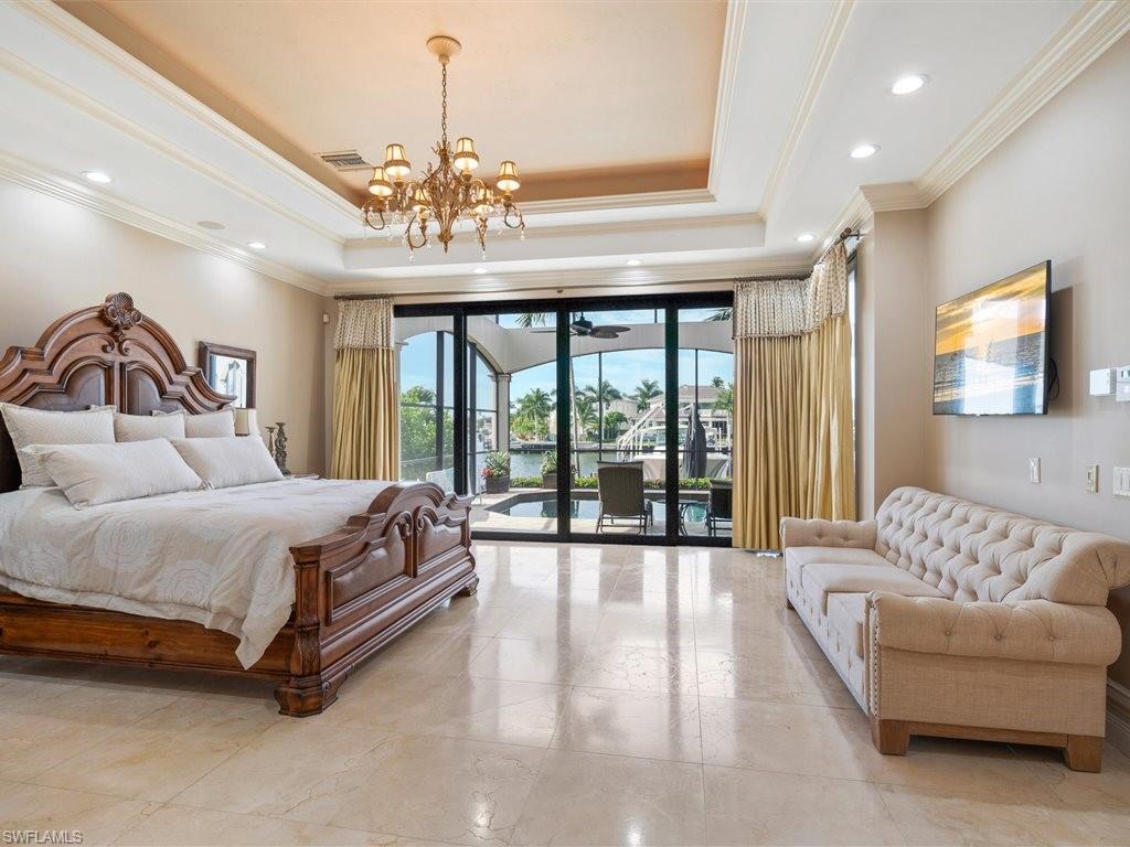 Bedroom featuring access to outside, a raised ceiling, ornamental molding, and a chandelier