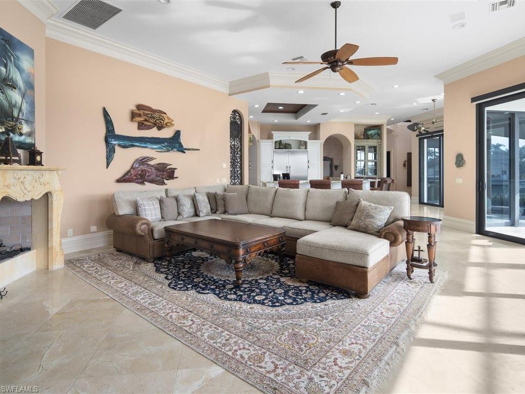 Living room featuring crown molding, arched walkways, ceiling fan, a fireplace, and recessed lighting