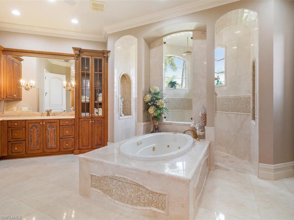 Full bathroom featuring a walk in shower, vanity, ornamental molding, and a whirlpool tub