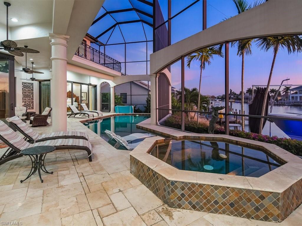 Pool at dusk with an in-ground hot tub, a lanai, an outdoor pool, and a sunroom