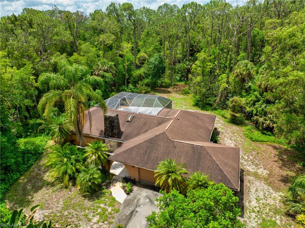 Aerial view of property and surrounding area featuring a forest