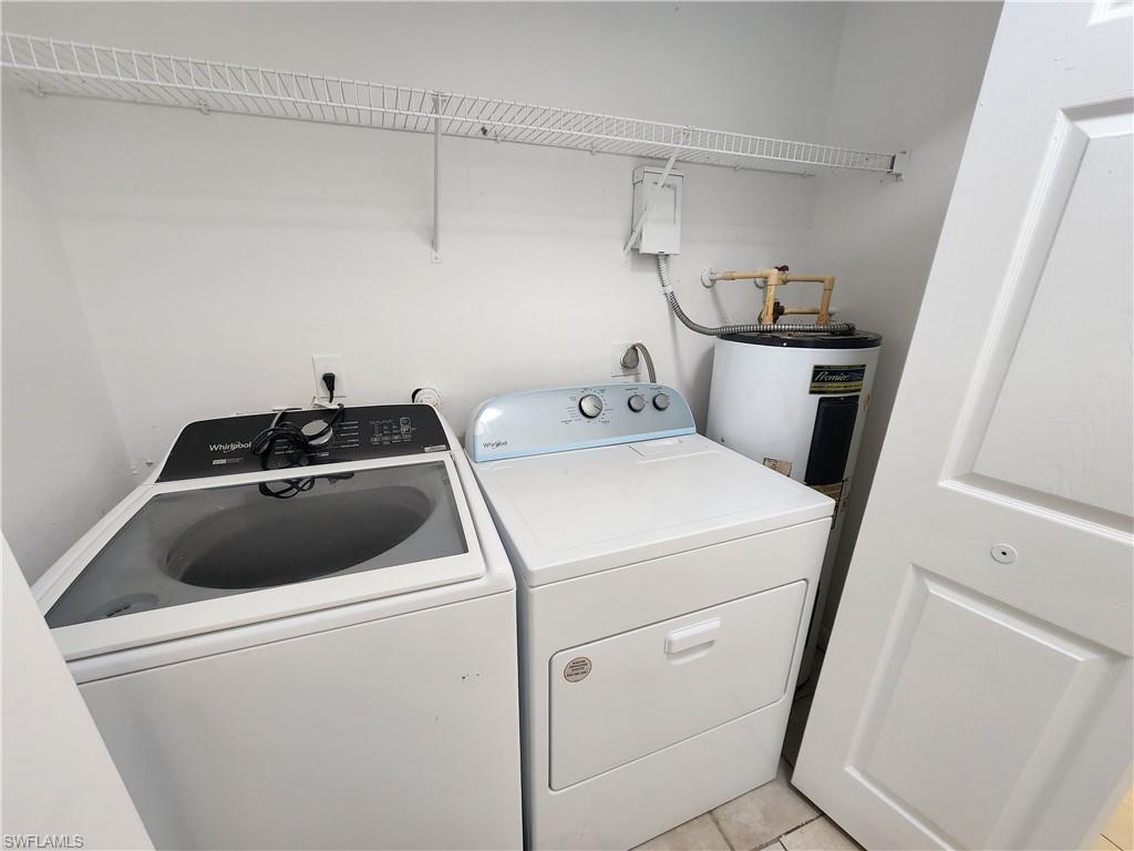 Washroom featuring separate washer and dryer, electric water heater, and light tile patterned flooring