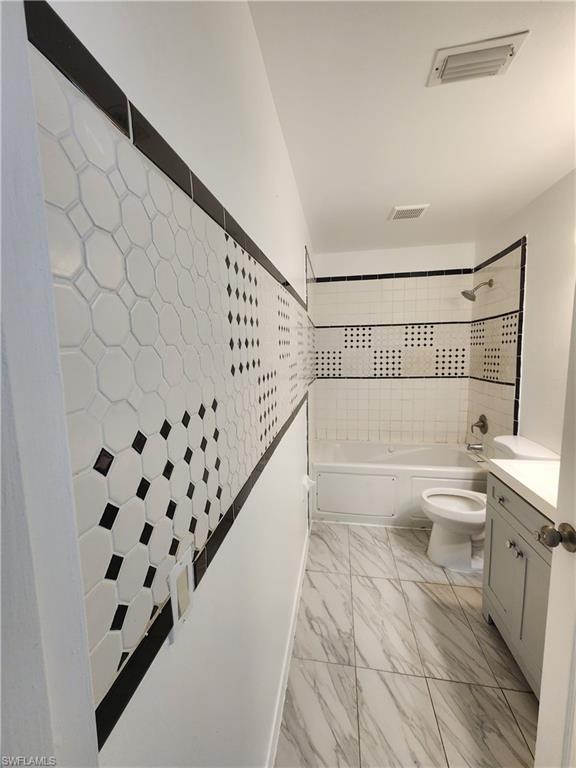 Full bathroom featuring shower / bathtub combination, vanity, and light marble finish flooring