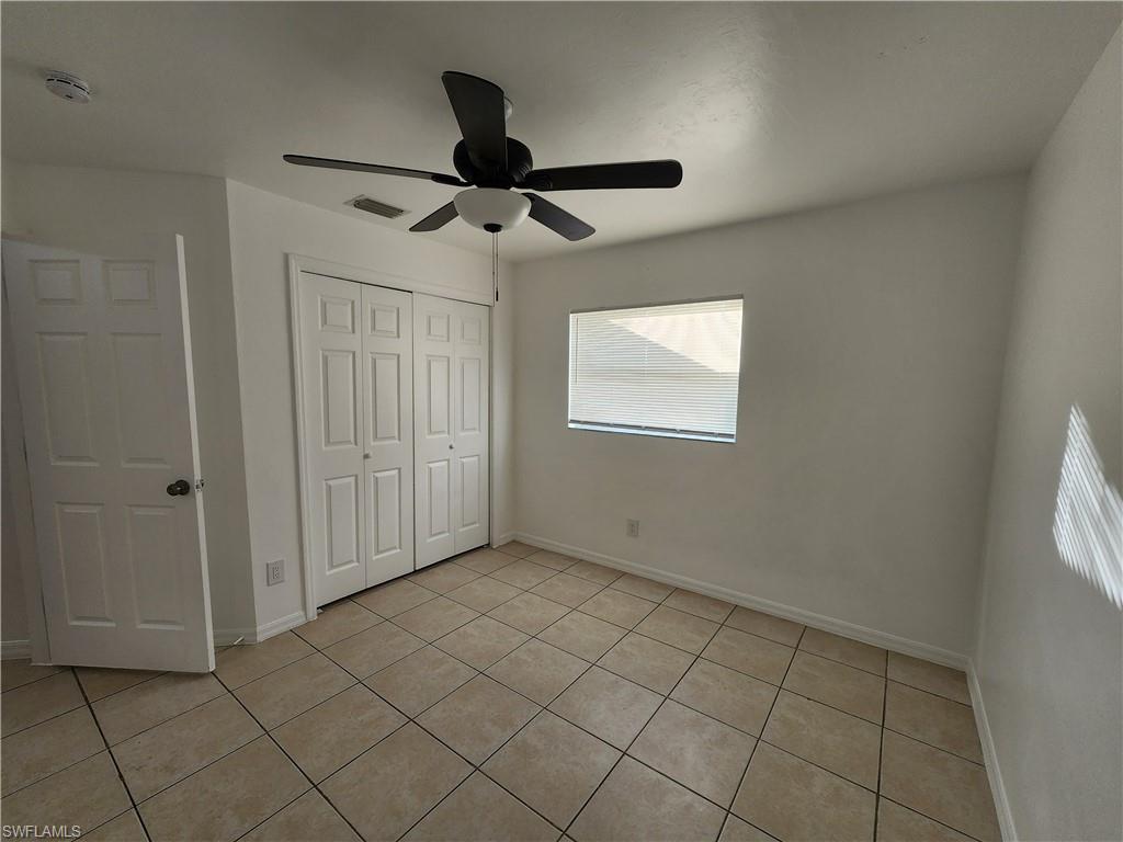 Unfurnished bedroom with a closet, a ceiling fan, and light tile patterned flooring