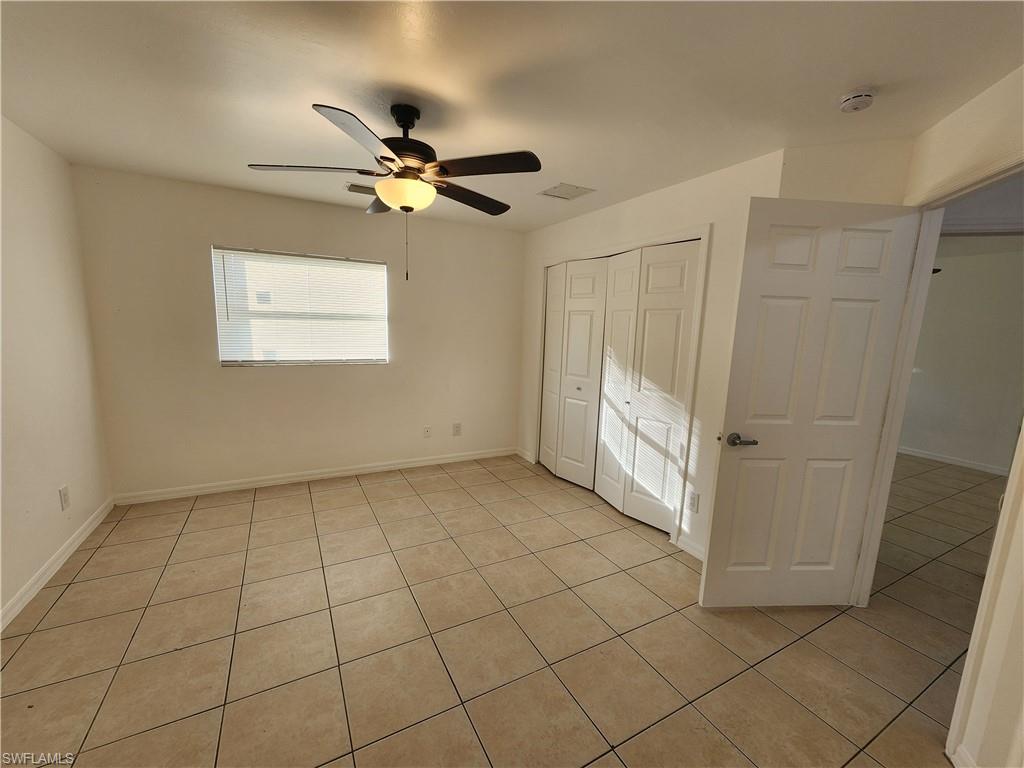 Unfurnished bedroom with a ceiling fan, a closet, and light tile patterned floors