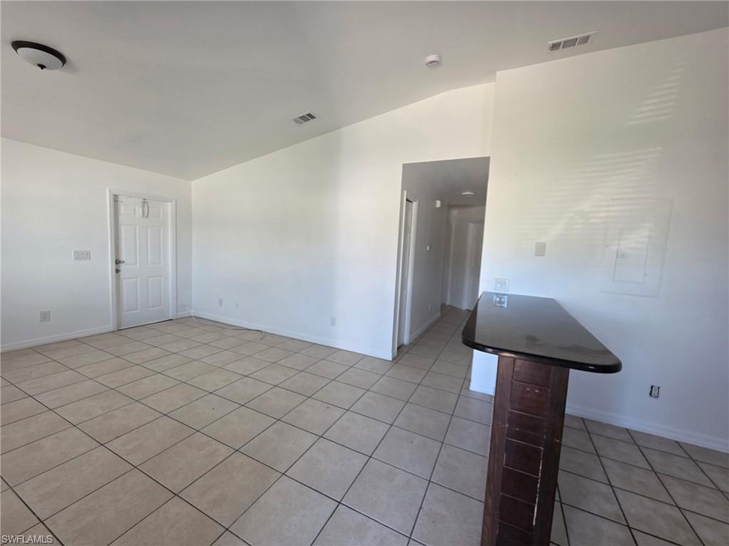 Empty room featuring vaulted ceiling and light tile patterned flooring