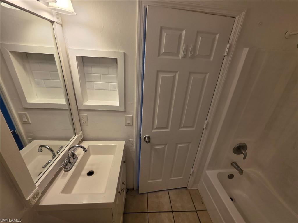 Bathroom featuring vanity, light tile patterned flooring, and shower / washtub combination