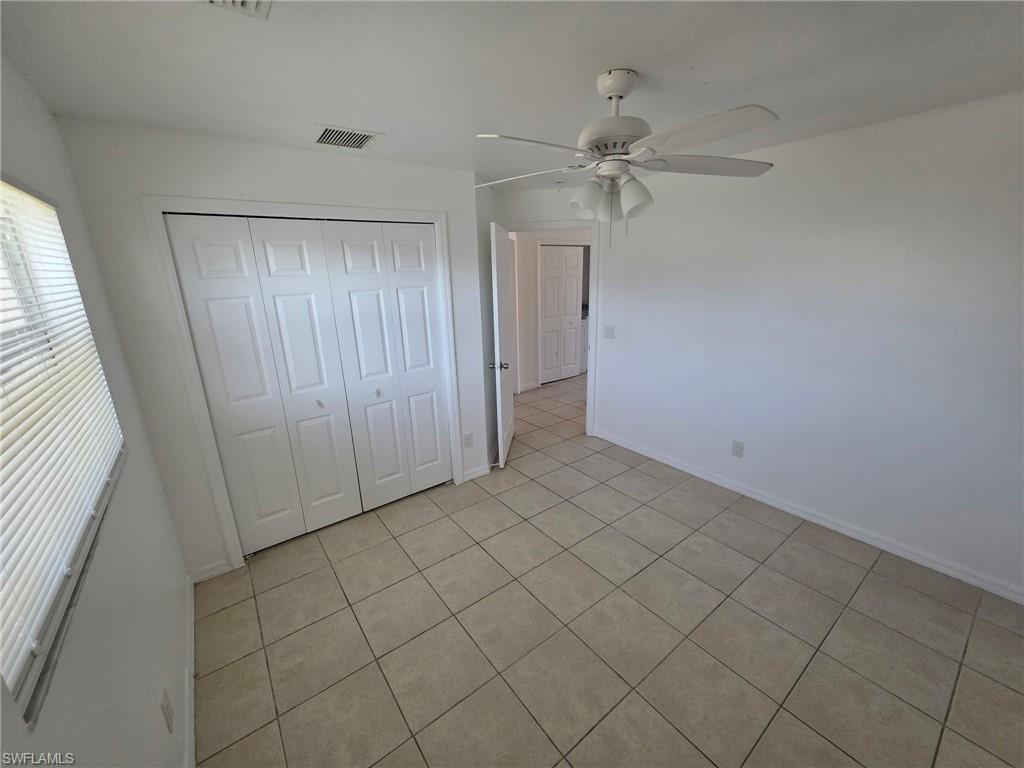 Unfurnished bedroom featuring a closet, ceiling fan, and light tile patterned floors
