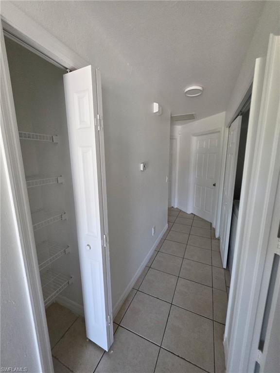 Corridor with light tile patterned floors and a textured ceiling
