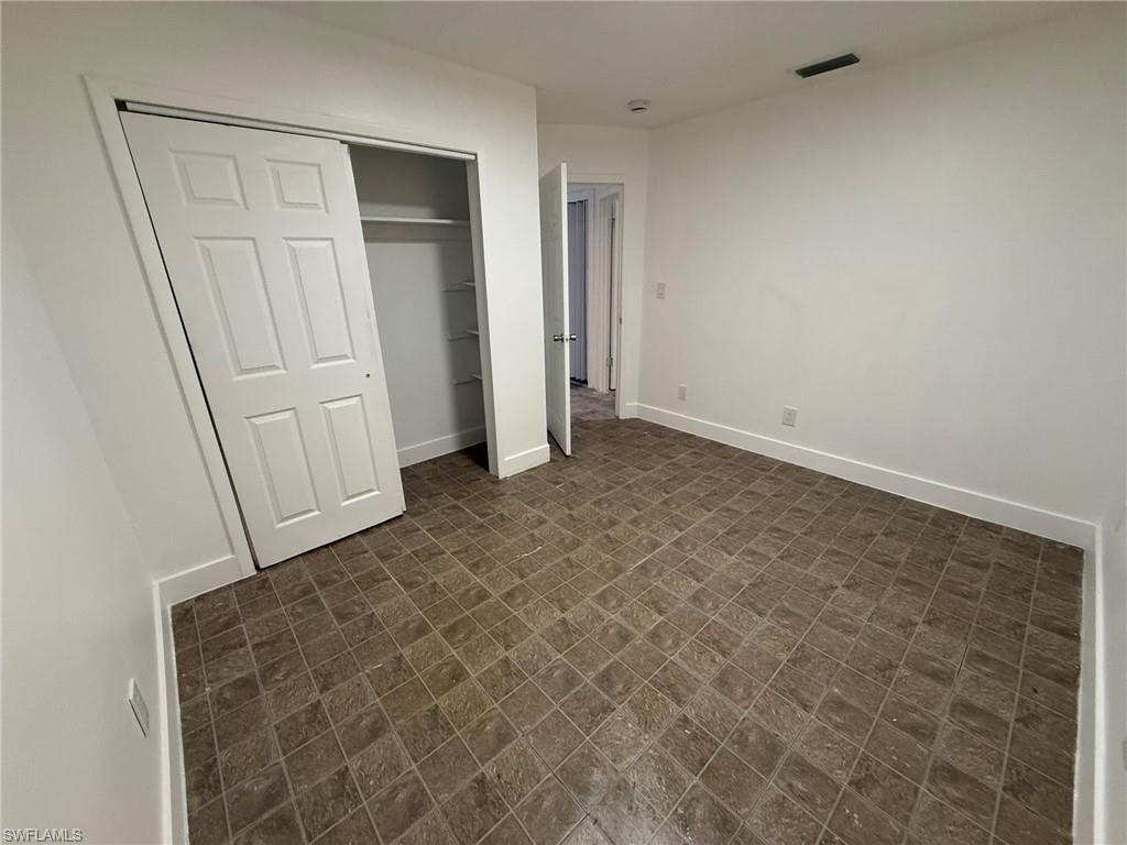 Unfurnished bedroom featuring a closet and brick patterned flooring