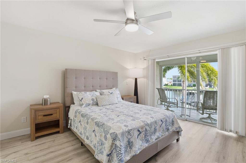 Bedroom featuring a water view, light wood-style floors, access to outside, and a ceiling fan