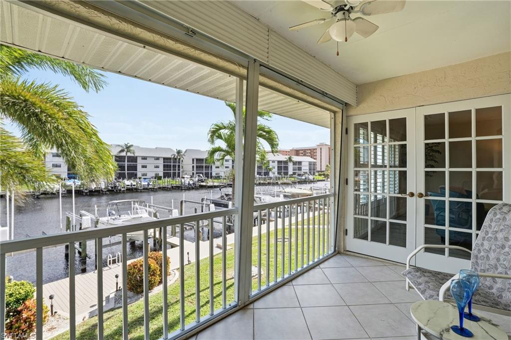 Balcony with a water view, a ceiling fan, a sunroom, and french doors